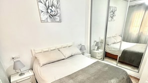 A bedroom with a bed, nightstands, a mirror, and a wall art piece. - 2BR Apartment Center of Torrevieja (Torrevieja)