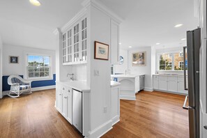 A spacious kitchen with white cabinetry, a built-in island, and a large window offering a view of the outdoors.