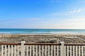 A beach view with a wooden fence in the foreground.