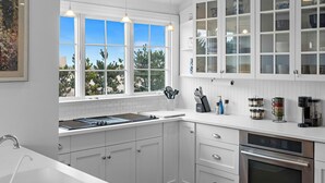 Una cucina moderna con mobili bianchi, forno integrato e una finestra vista alberi.
