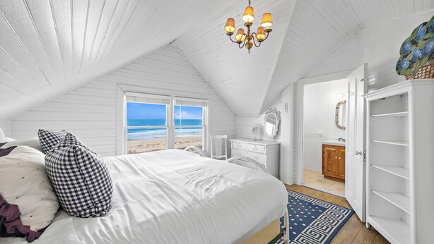 Una camera da letto con un grande letto, un lampadario, vista sulla spiaggia e cabina armadio.