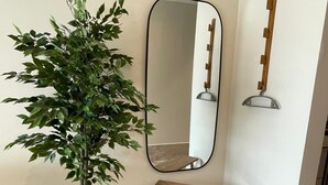 A corner with a potted plant, a mirror, and a wooden bench. - Studio 104 in Distrito Puerto (Puerto Morelos)