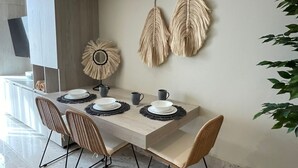 A modern dining area with a light-colored table set for four, surrounded by wooden chairs with metal legs. - Studio 104 in Distrito Puerto (Puerto Morelos)