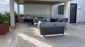 A modern outdoor patio with a sofa, dining table, and chairs. - Studio 104 in Distrito Puerto (Puerto Morelos)