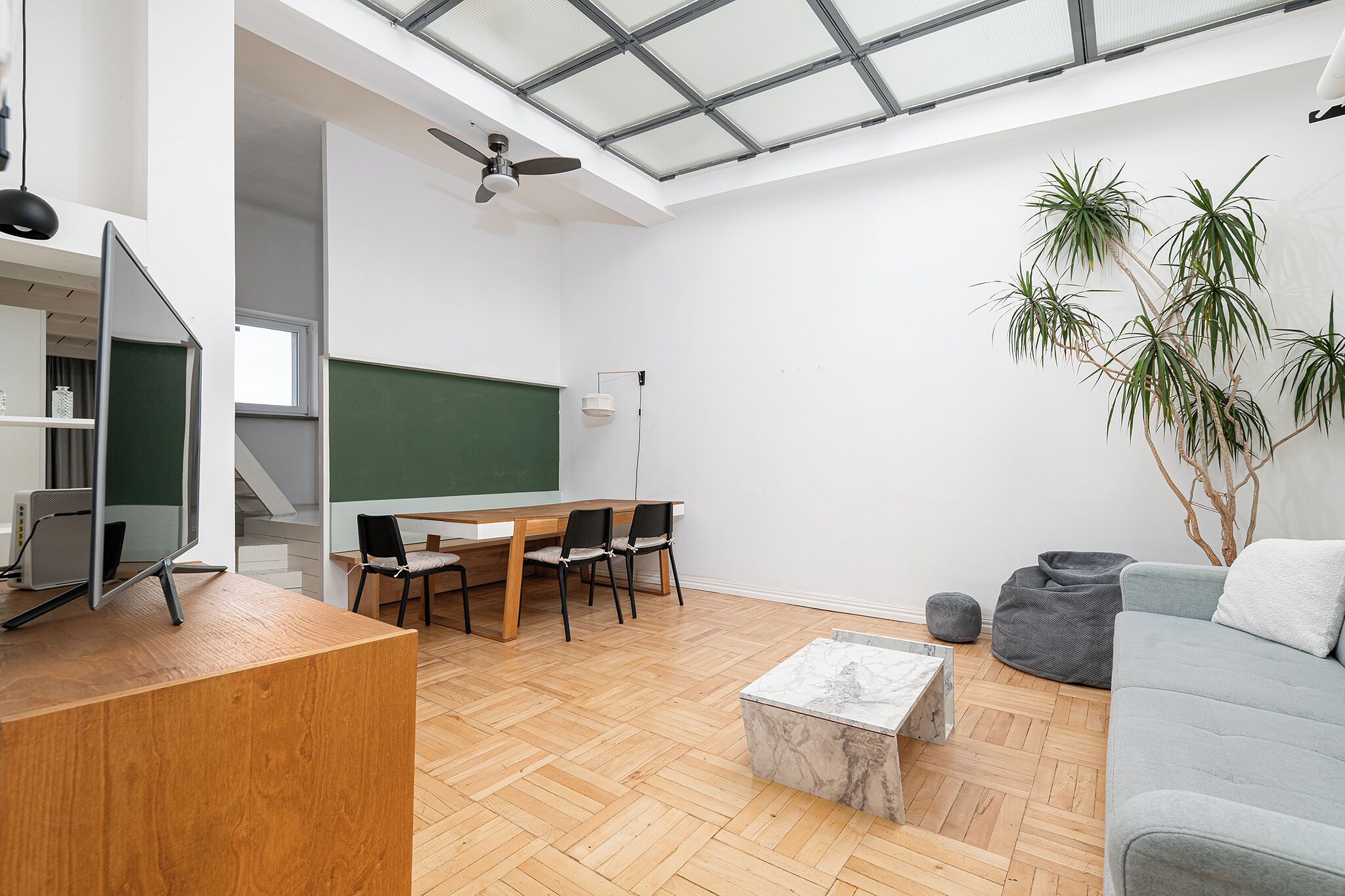 A modern classroom with a wooden desk, chairs, a blackboard, and a ceiling fan.