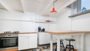 A modern kitchen with white cabinets, a wooden countertop, a black oven, and a colorful tiled floor. - RentPlanet - Apartament Krucza (Warsaw)