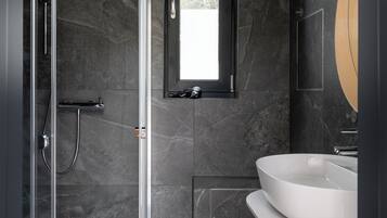 Un baño moderno con cabina de ducha de vidrio, un lavamanos y un espejo.