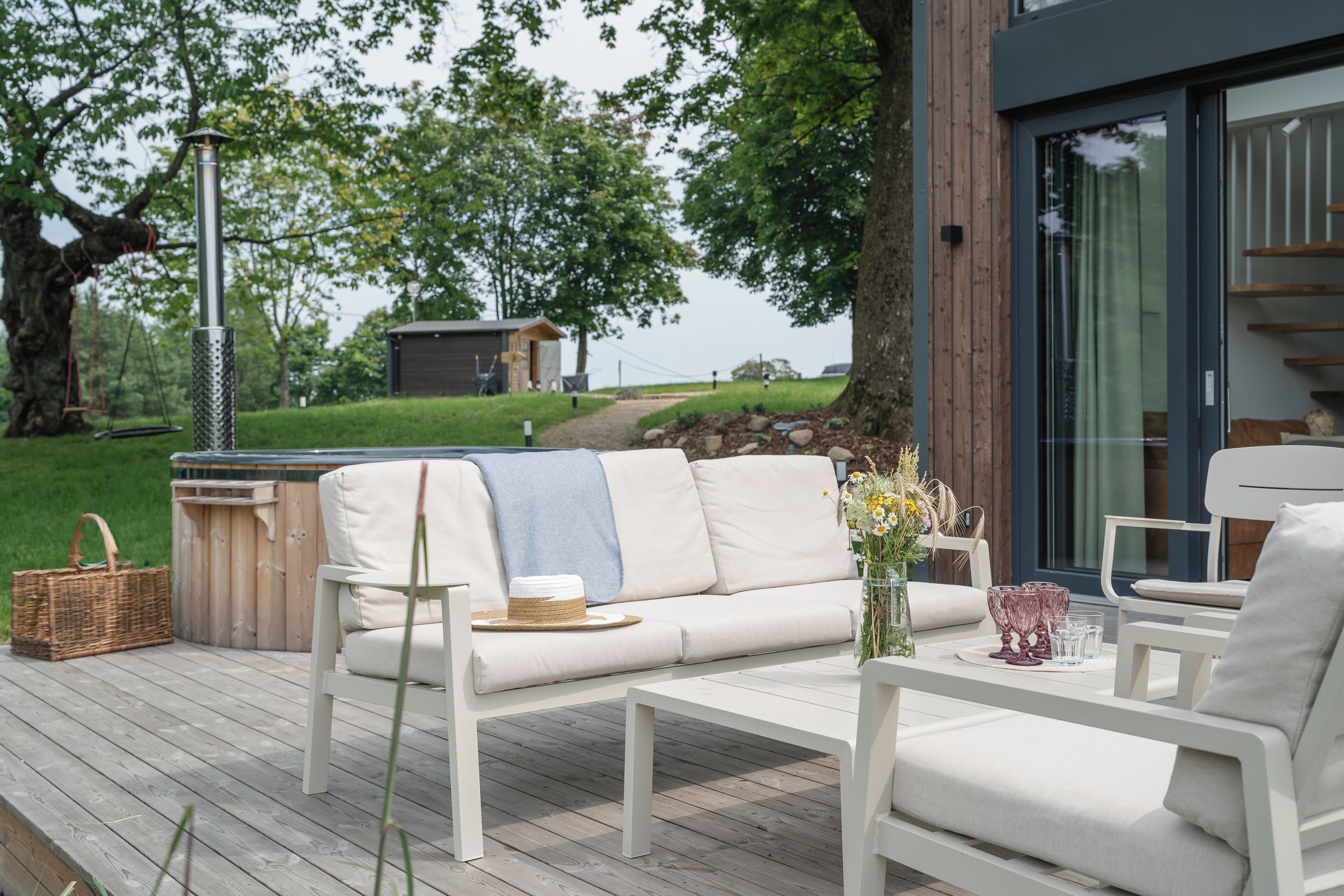 A deck with a white sofa, a coffee table, and a wicker basket.