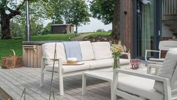 A deck with a white sofa, a coffee table, and a wicker basket.