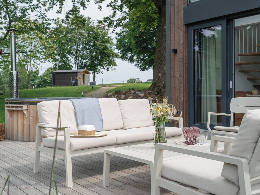 A deck with a white sofa, a coffee table, and a wicker basket.