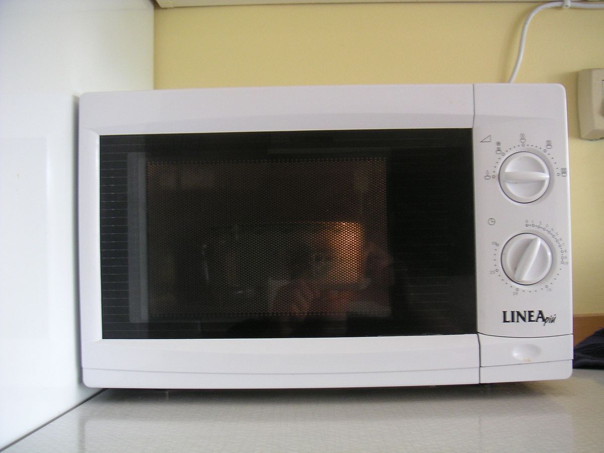 A white microwave oven with two dials and a digital display, placed on a kitchen counter.