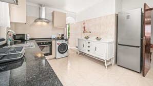 A modern kitchen with a stainless steel refrigerator, a built-in washing machine, and a white cabinetry set.