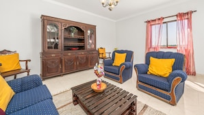 A living room with a sofa, armchair, wooden cabinet, and a coffee table.