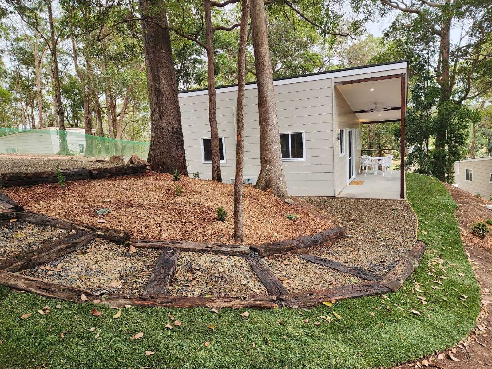 Una casa moderna con un porche cubierto, rodeada de árboles y un césped cuidado.