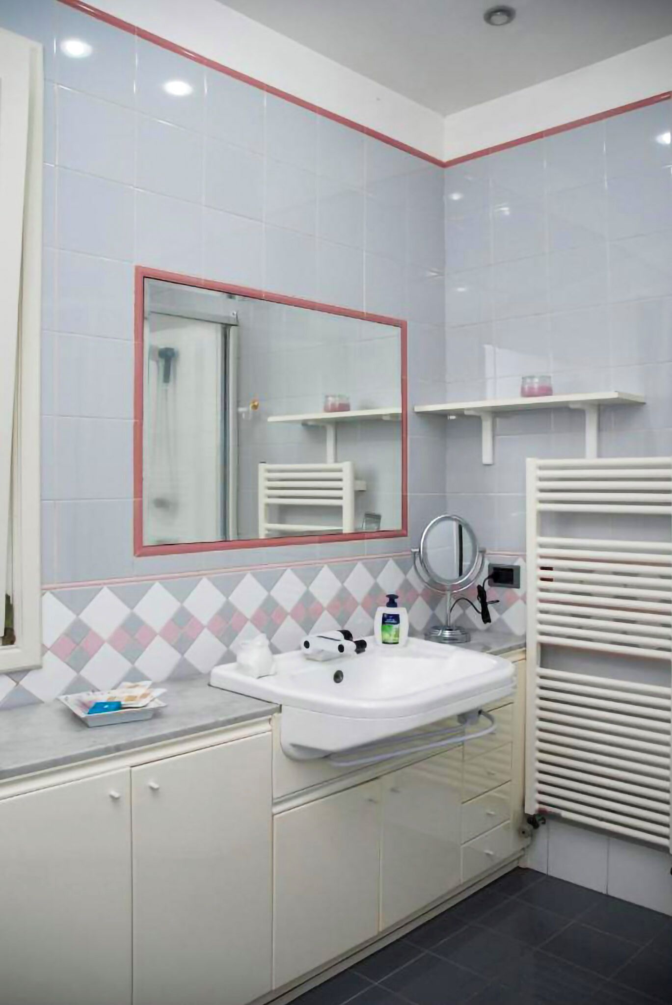 Un baño con un lavabo blanco, un espejo y un perchero para toallas.