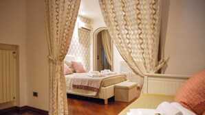 A bedroom with a bed, a bedside table, and a chair. There is a window with curtains, a radiator, and a mirror on the wall. - Villa with private Pool (Ispica)