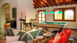 A spacious room with a pool table, a fireplace, and a cozy seating area with a red sofa. - Villa with private Pool (Ispica)