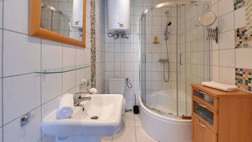 Een moderne badkamer met een glazen douchecabine, een witte wastafel en een houten meubel.