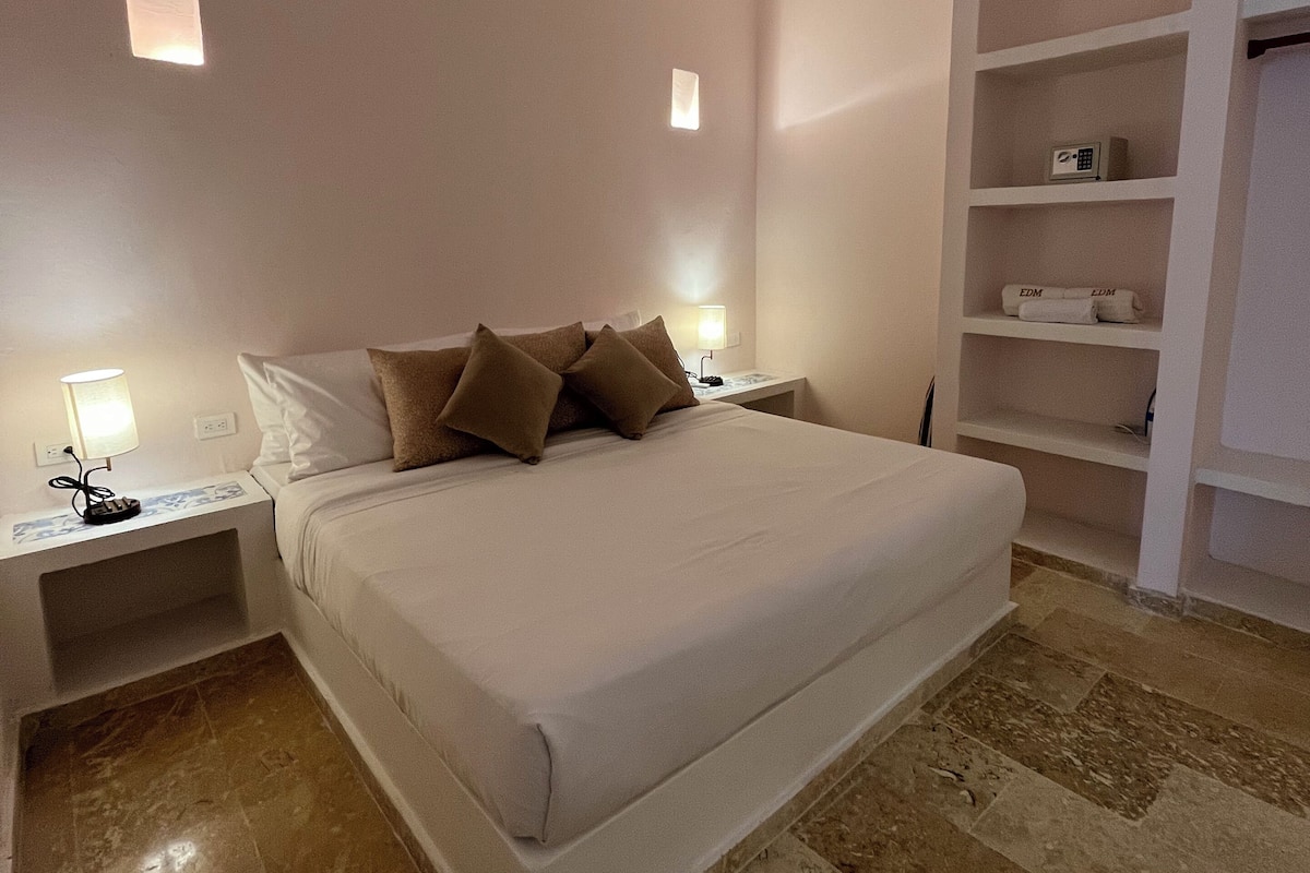 A bedroom with a bed, nightstands, a ceiling fan, a wall-mounted shelf, and a marble floor.