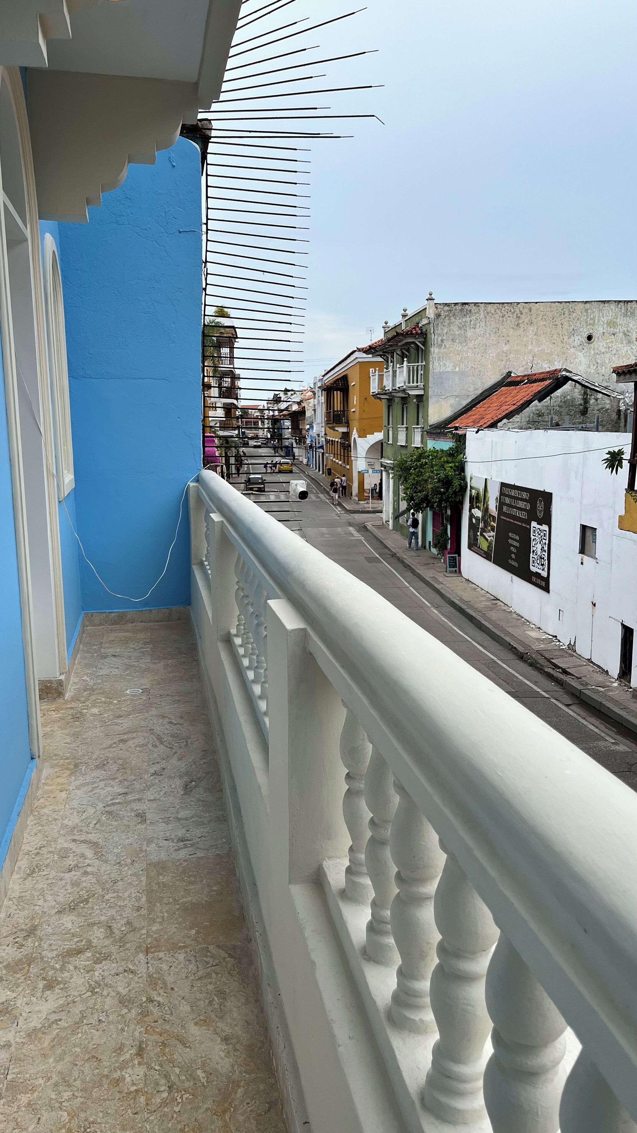 A balcony with a white balustrade overlooking a street with buildings.