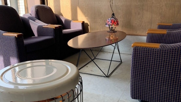 Ein gemütlicher Sitzbereich mit rundem Tisch und zwei Sofas, einer dekorativen Lampe und einem tragbaren Heizlüfter.