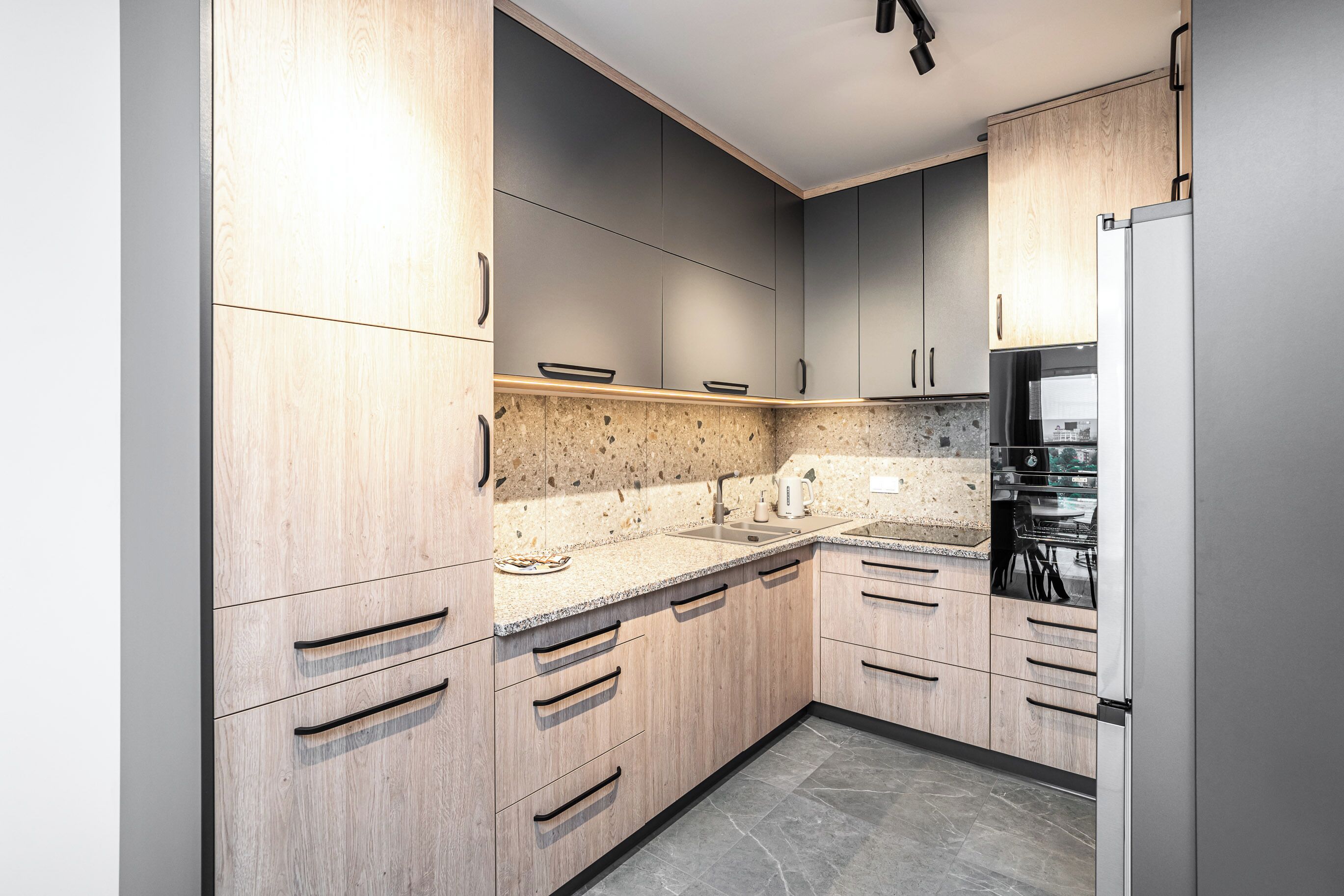 Eine moderne Küche mit Holzausstattung, Granitarbeitsplatten und einem eingebauten Backofen.