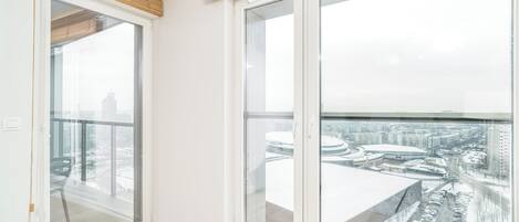 A room with large windows, a view of a cityscape, and a wooden floor.