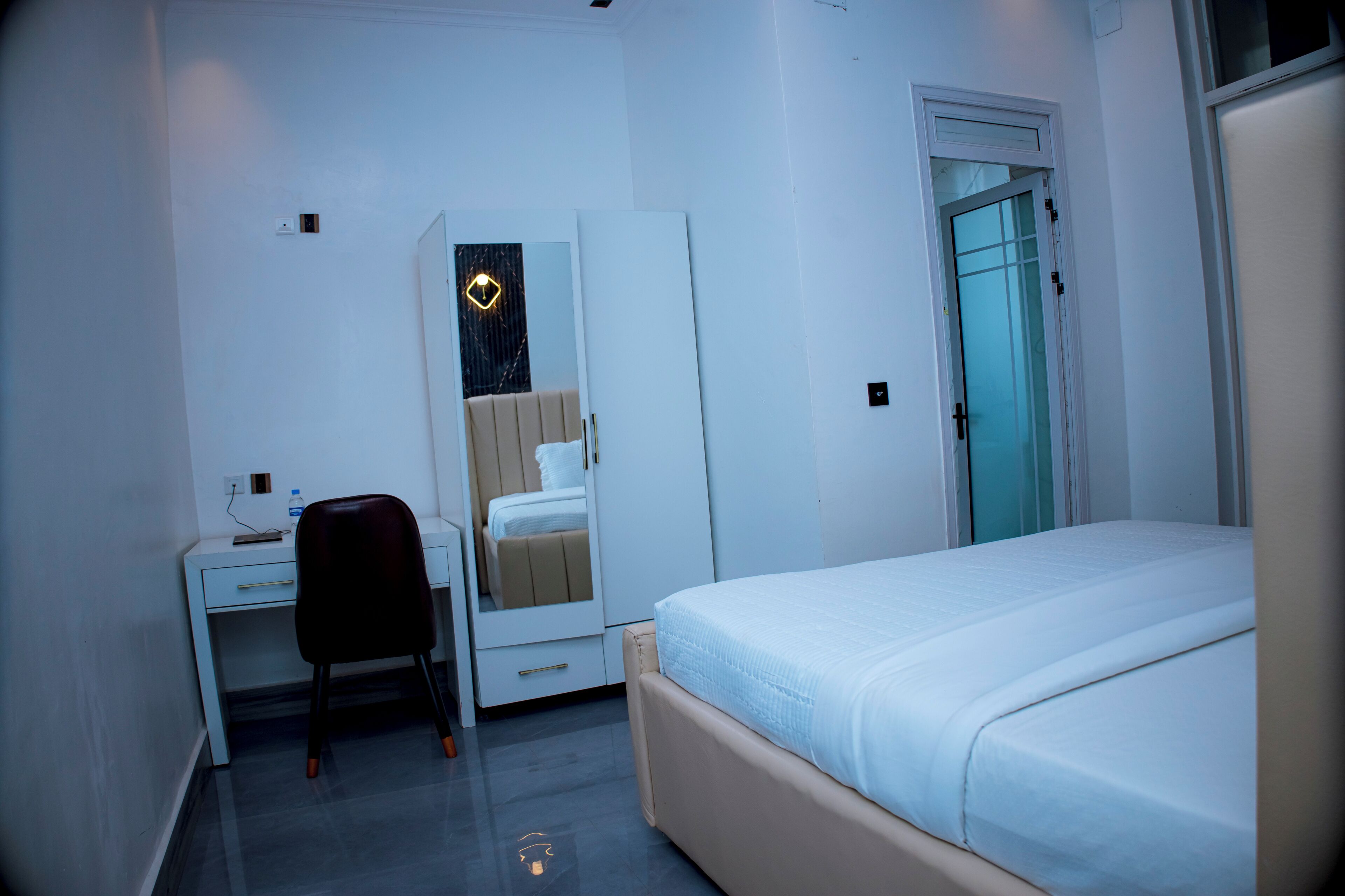 A bedroom with a bed, a desk, a chair, a wardrobe, and a door.