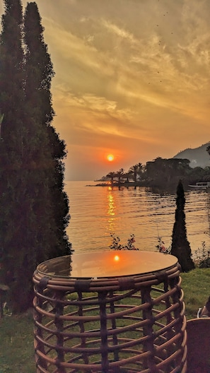 A sunset view over a body of water with a chair in the foreground. - Kivu hilltop Beach Hotel & Apartment (Nyayumba)