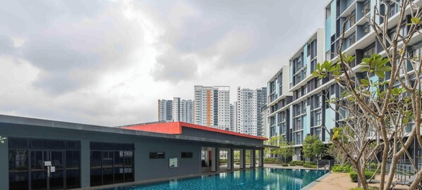 A modern building with a swimming pool, surrounded by high-rise residential buildings.