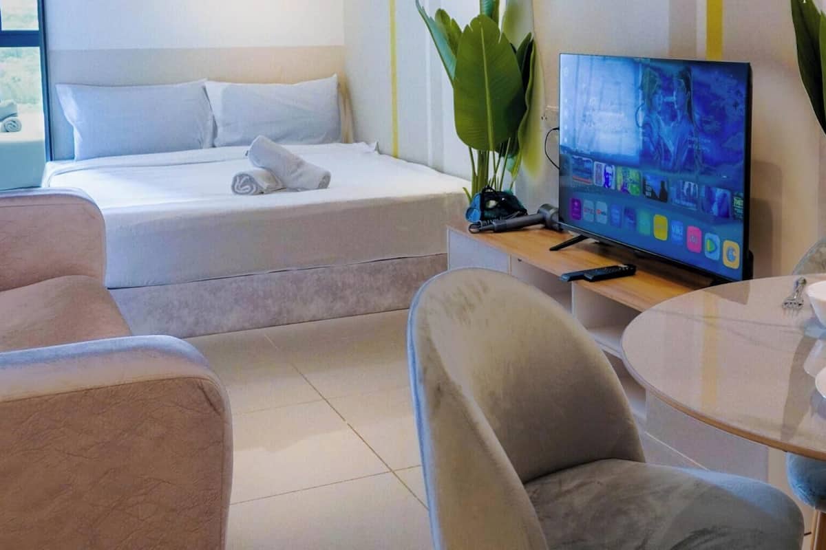 A hotel room with a bed, a TV, a dining table with plates, and chairs.