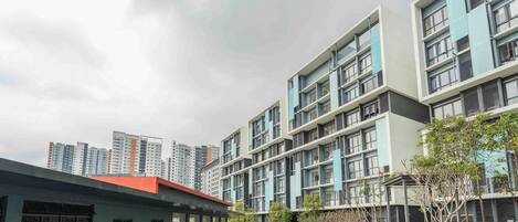 Um edifício residencial moderno de vários andares, com telhado plano, janelas amplas e varanda visível.