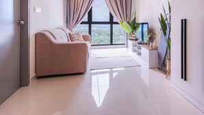A modern living room with a sofa, a large window with curtains, a plant, and a minimalist decor. - Core Soho Suites Sepang by The Stay Hub (Sepang)