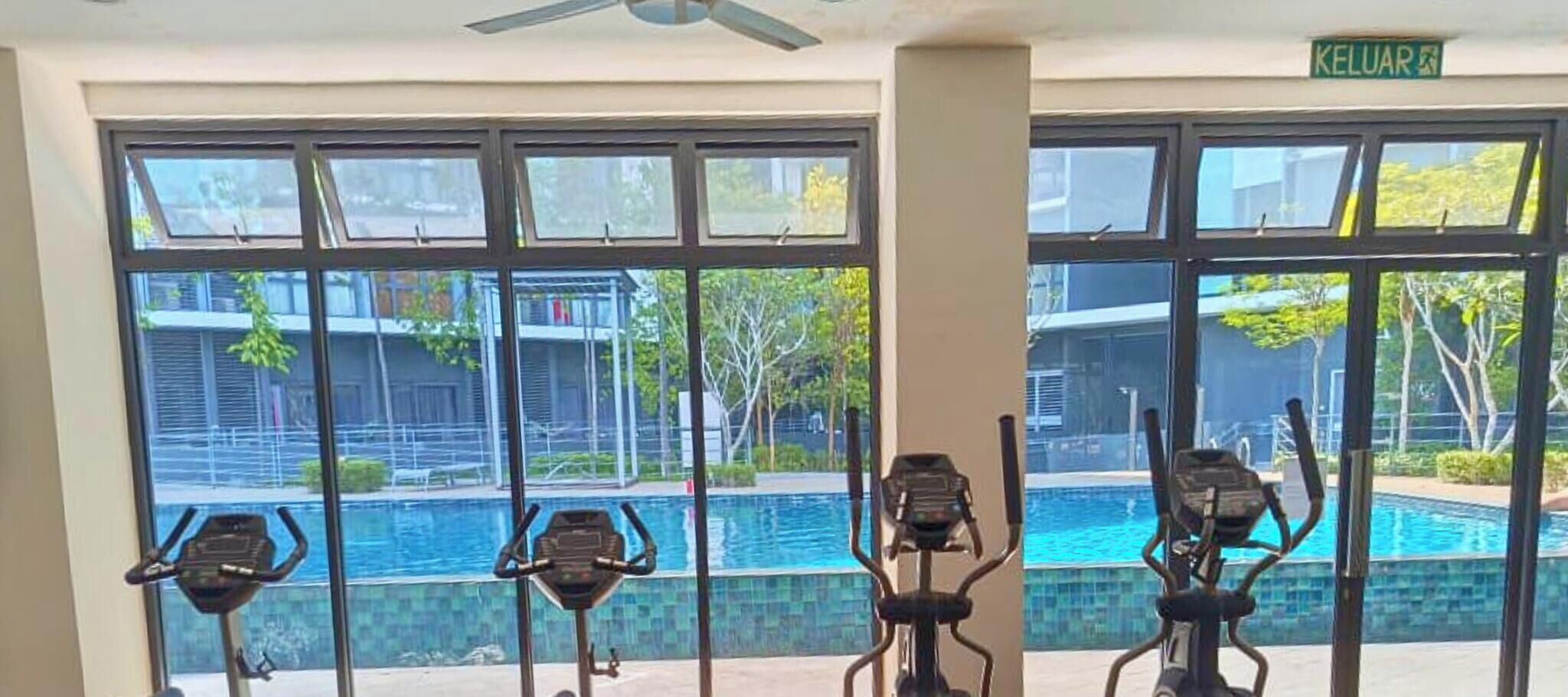 A gym with stationary bikes and a view of an outdoor swimming pool.