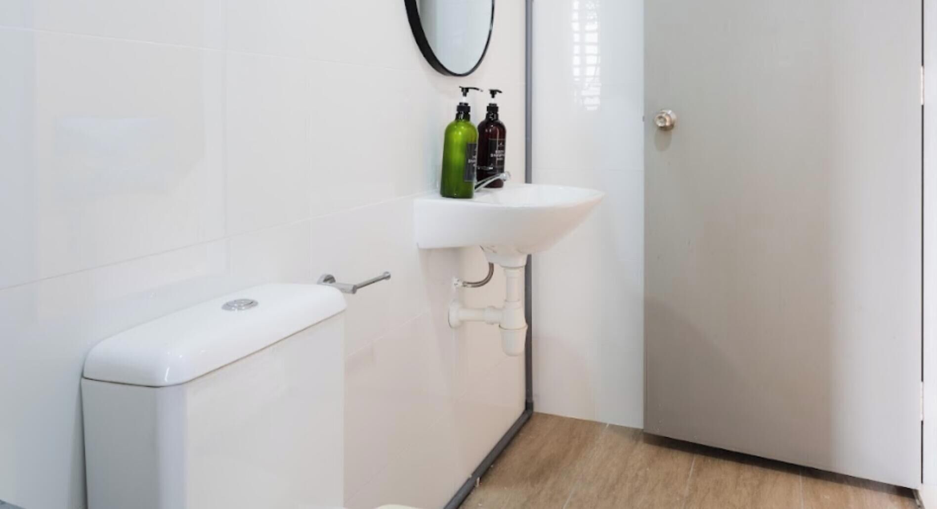 Ein Badezimmer mit Toilette, Waschbecken und zwei Flaschen an der Wand.