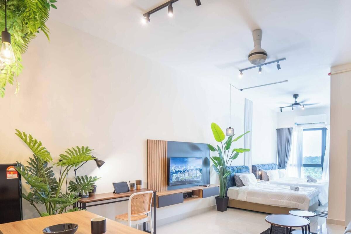 A modern hotel room with a bed, a desk with a laptop, a TV, and a balcony with a view.
