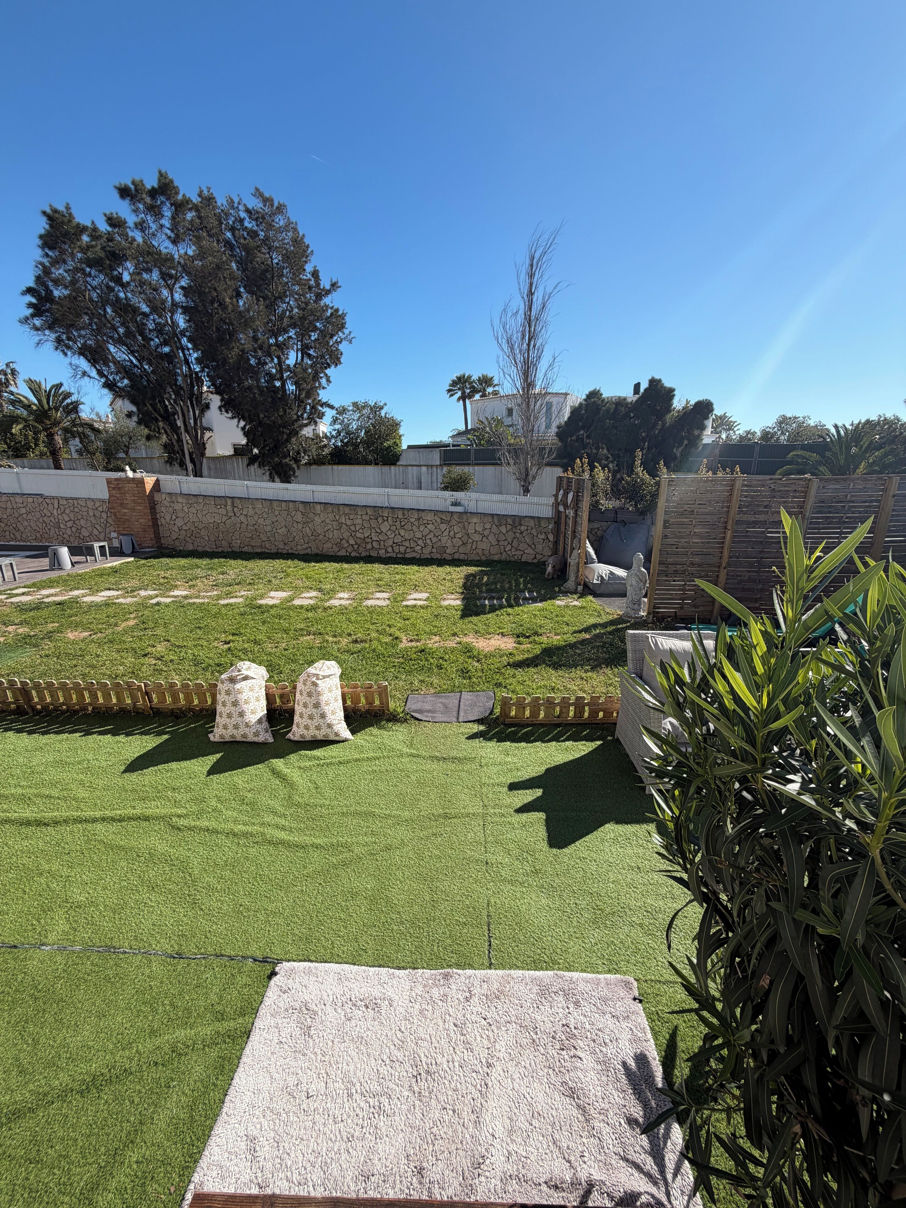 A well-maintained outdoor area with artificial grass, a stone wall, and a wooden fence.