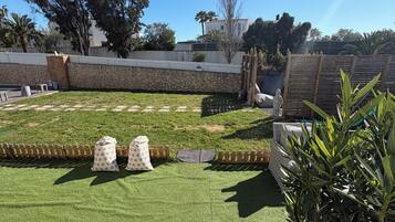 A well-maintained outdoor area with artificial grass, a stone wall, and a wooden fence.