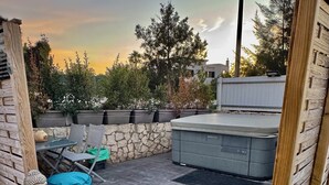 A rooftop garden with a seating area, a hot tub, and two Buddha statues.