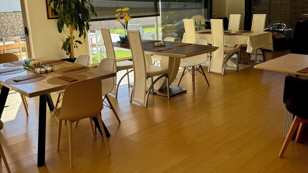 A modern dining area with a wooden table, white chairs, and a potted plant.