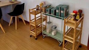 A room with a wooden desk, a black chair, and a glass shelf with jars and containers.