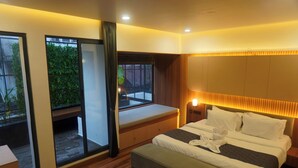 Habitación de hotel moderna con una cama grande, un banco junto a la ventana y vistas a zonas verdes.