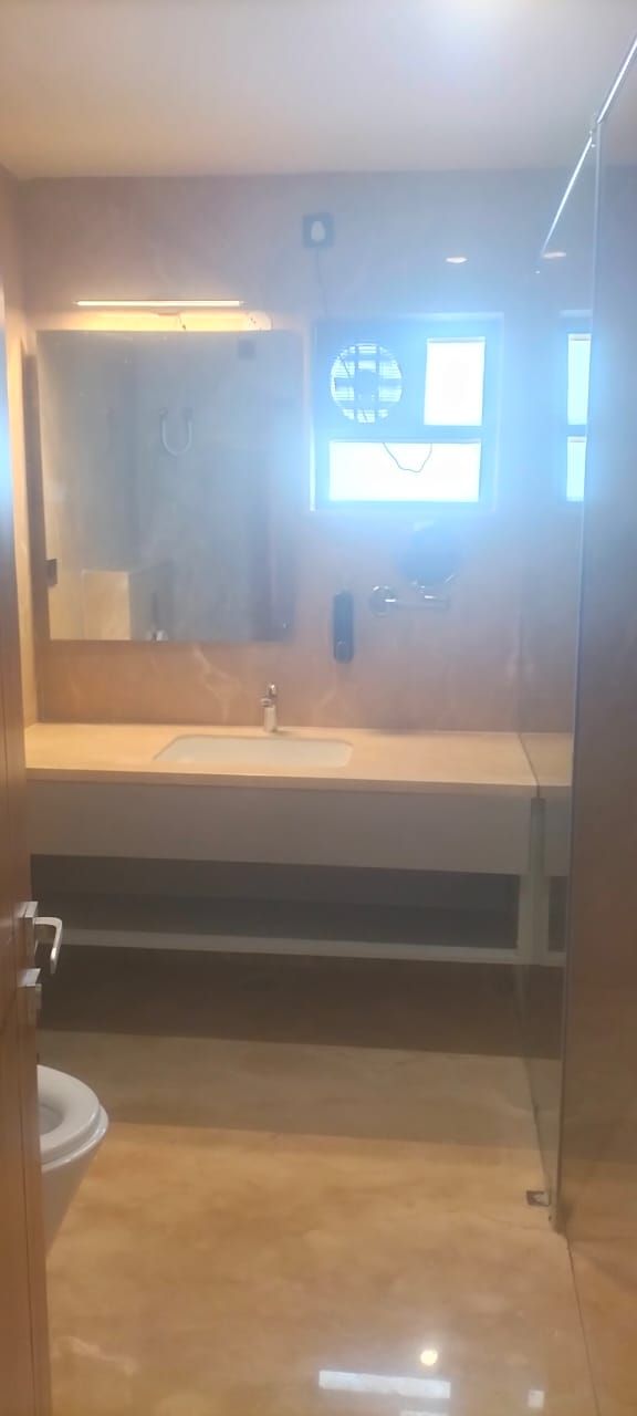 Et badeværelse med et stort spejl, håndvask og toilet.