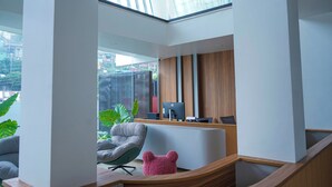 Una zona de recepción moderna con un escritorio de madera, computadora y asientos.