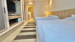Quarto de hotel com duas camas, televisão, armário de madeira e tapete listrado.