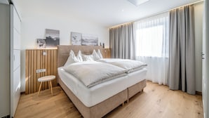 Ein modernes Schlafzimmer mit einem großen Bett, einem kleinen Tisch und Kunstwerken an der Wand.