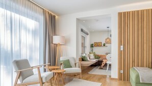Ein modernes Wohnzimmer mit einer Couch, Sesseln, einer Lampe und einer Holzwand.