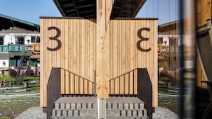 Eine Holzhütte mit den Zahlen '3' und '8', die zu einer Treppe aus Stein führt.