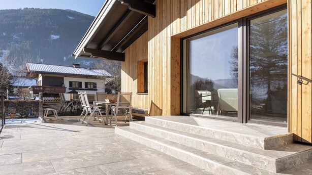 Ein Holzgebäude mit Terrasse, Gartenmöbeln und Bergblick.