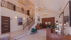 Un vestíbulo de hotel con una escalera, una zona de estar y un mostrador de recepción.